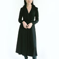 Woman wearing Werable's black long sleeve wrap dress with knee high black boots.