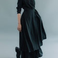 Woman wearing Werable's black long sleeve wrap dress with boots, posing