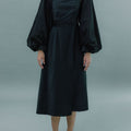 Front view of woman wearing transformable bolero and cross-back dress in black.