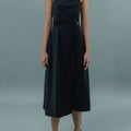 Front view of a woman wearing Werable's black cross back dress, with an magnetic buckle on the waistline.