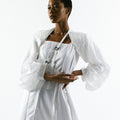 Woman in Werable's bolero in an arm sling and wrap dress in white.