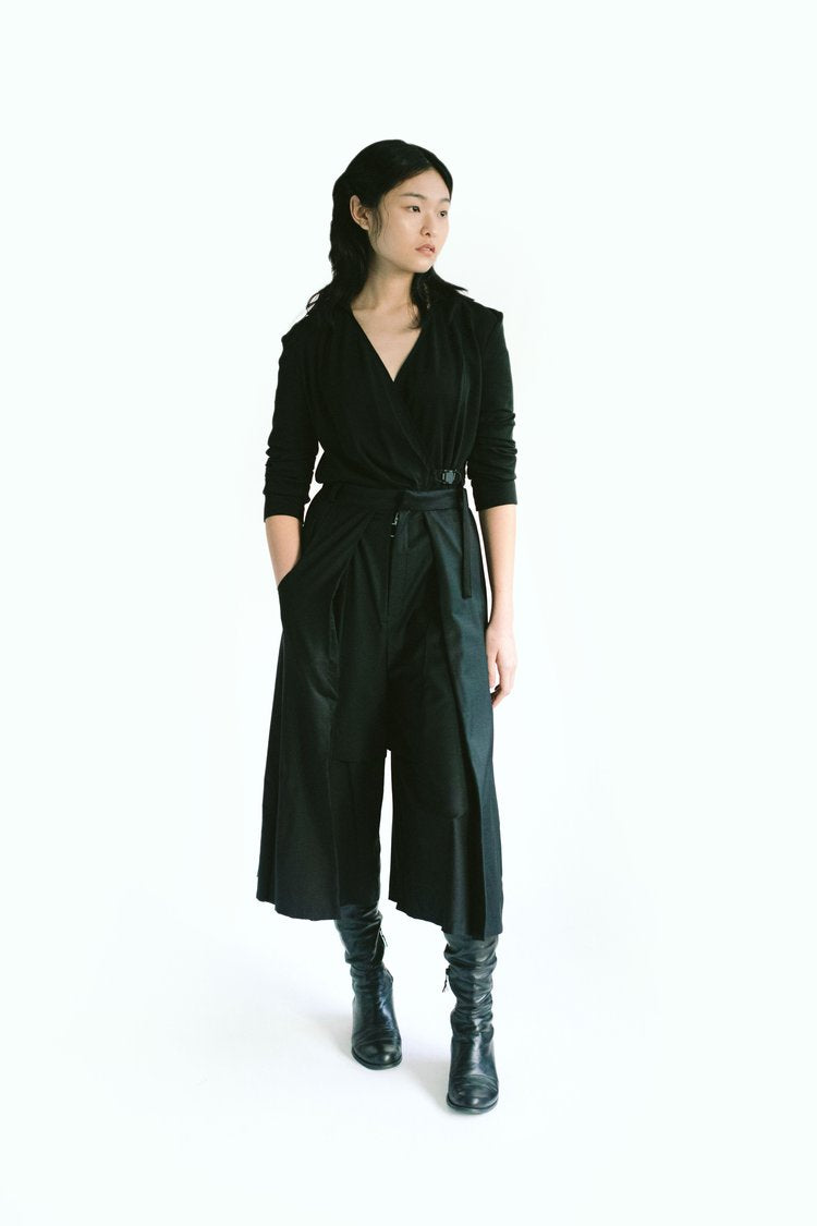 Front view of a woman wearing Werable's easy-grip buckle wrap shirt with hakama culottes in black. 