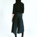 Back view of a woman wearing Werable's easy-grip buckle wrap shirt with hakama culottes in black. 