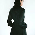 Back view of a woman in a Werable's black cotton coat, with her head turned slightly to the side