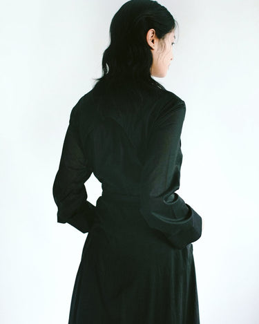 Back view of a woman in a Werable's black cotton coat, with her head turned slightly to the side