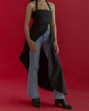 Front view of Werable's matisse halter dress in black, paired with blue jeans and black boots.