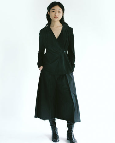 Front view of a woman wearing Werable's easy grip buckle wrap shirt with hakama culottes in black. 